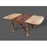 A 1930's oak drawer leaf extending dining table raised upon turned legs with stretchers, together