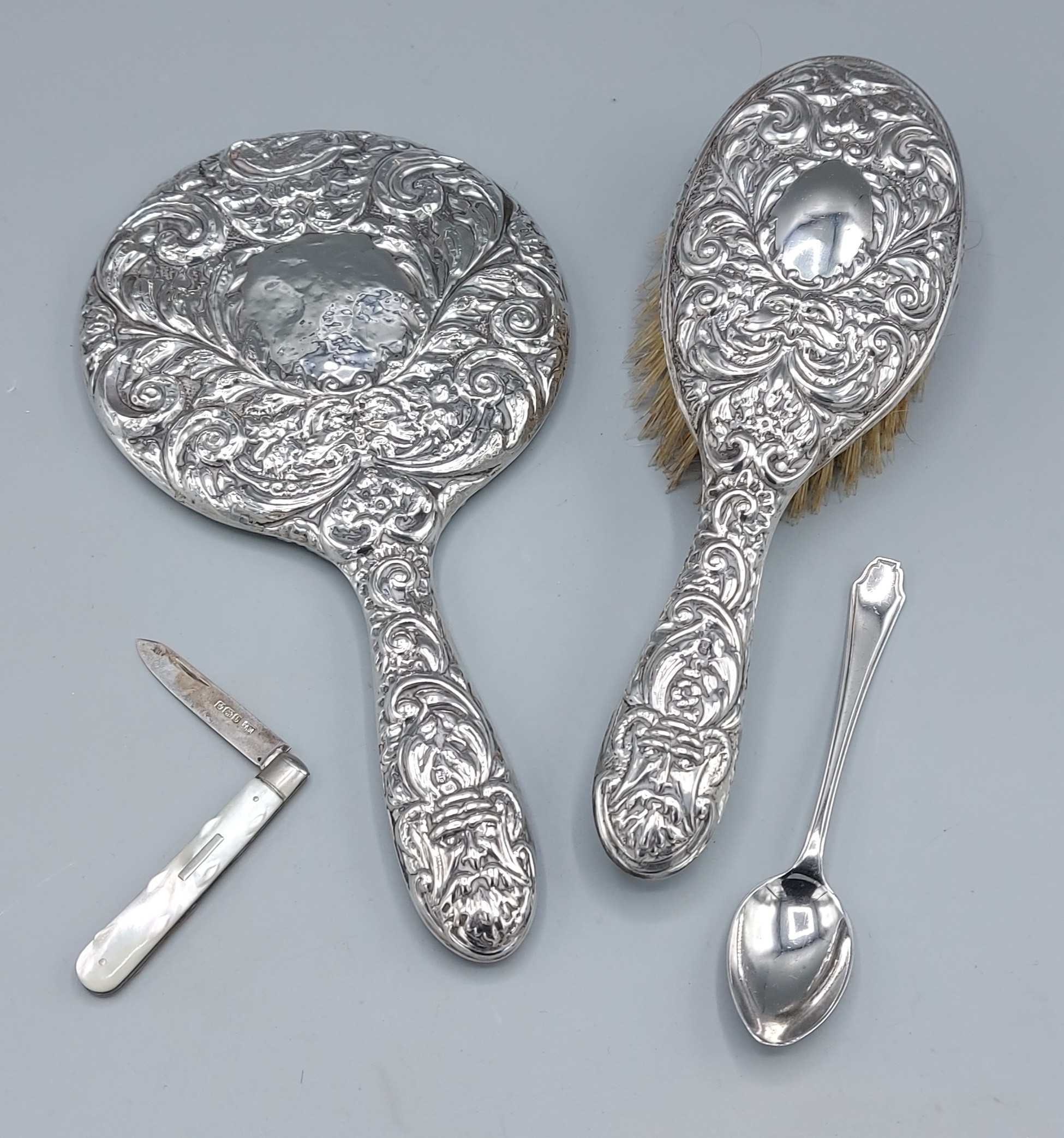 A Birmingham silver backed hand mirror with embossed decoration together with a matching brush, a