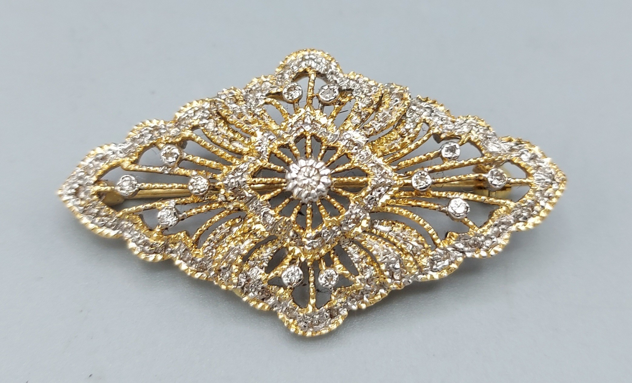 An 18ct gold brooch of pierced shaped form set with Diamonds, 8gms