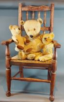 A plush teddy bear together with two other teddy bears and an elm spindle back arm chair with rush