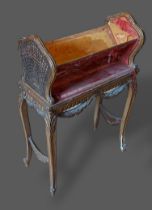 A French gilded bookstand with cane ends raised upon cabriole legs with scroll feet, 49cms wide,