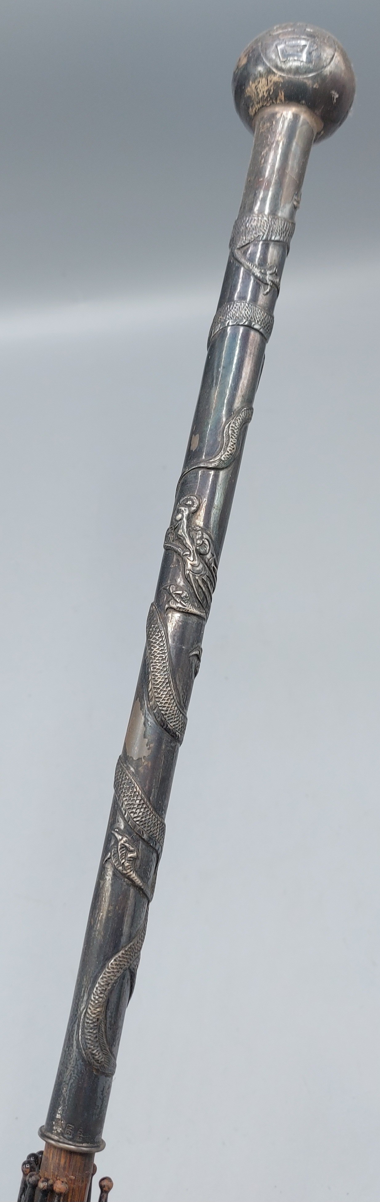 A Chinese white metal Parasol handle decorated with serpents, 101cms long
