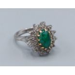 An 18ct white gold Emerald and Diamond cluster ring, with an oval Cabochon Emerald surrounded by