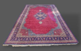 A North West Persian woollen carpet, with central medallion upon a red and blue ground within