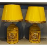 A pair of Toleware table lamps, each decorated with a crest upon a mustard ground, complete with