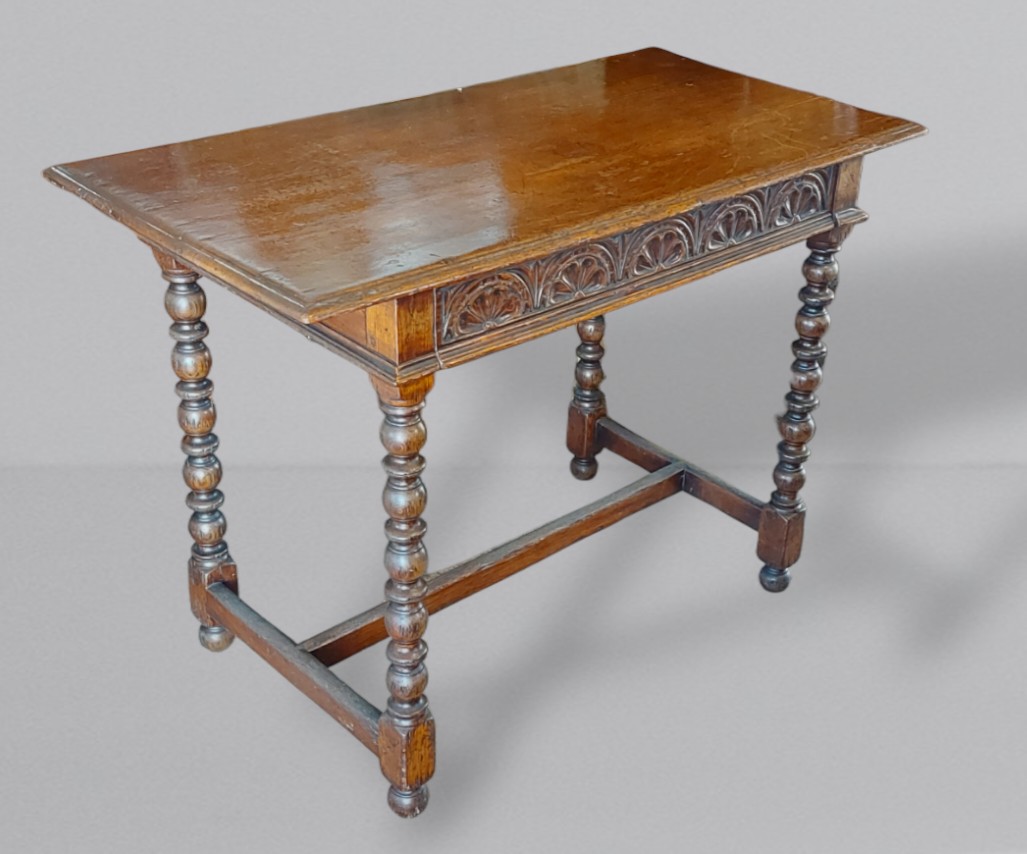 An oak side table, the moulded top above a carved frieze drawer, raised upon knopped legs with