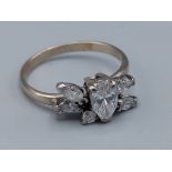 An 18ct white gold ring set with a central pear shaped Diamond flanked by other Diamonds, 3.3gms,