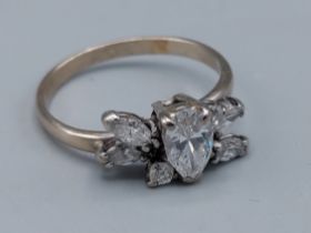 An 18ct white gold ring set with a central pear shaped Diamond flanked by other Diamonds, 3.3gms,