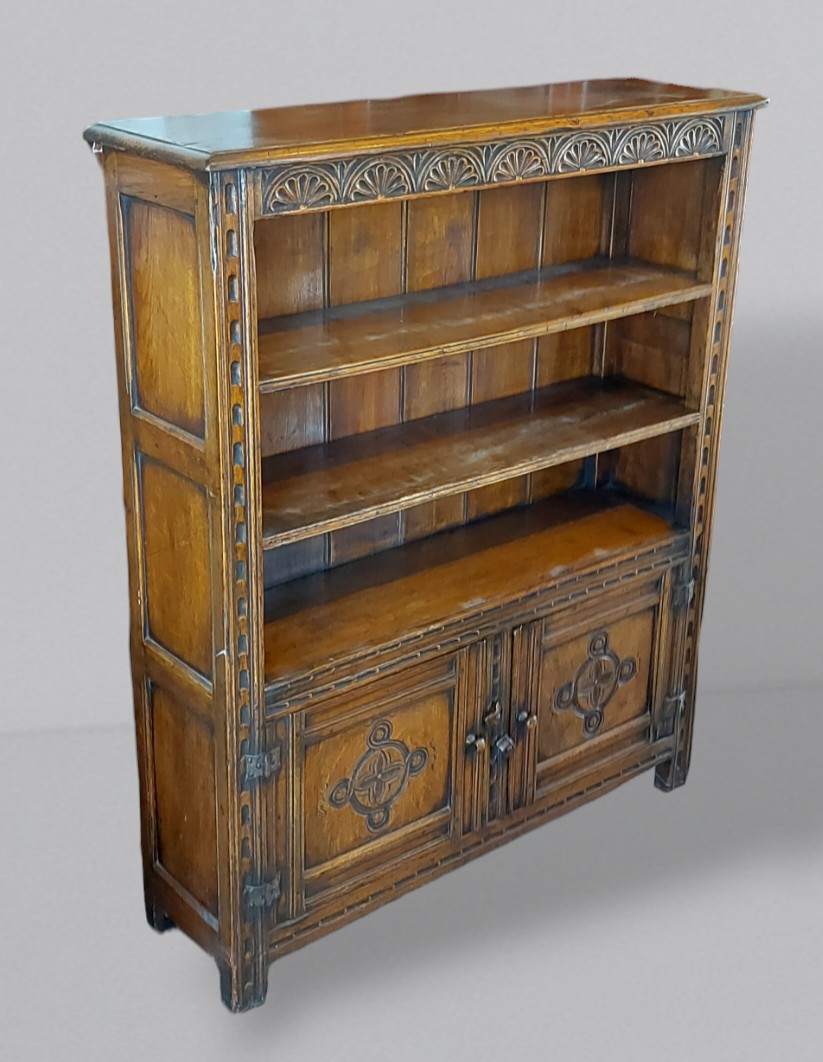 An oak bookcase with open shelves above two doors flanked by stiles, 95cms wide, 28cms deep and