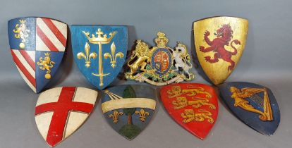 A collection of seven wooden shields, each painted with a crest together with a gilt metal coat of