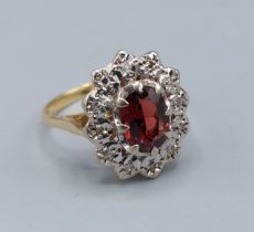 An 18ct gold cluster ring set with a central oval Garnet surrounded by Diamonds, 3.8gms, ring size M