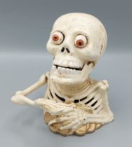 A painted cast iron money box in the form of a skeleton, 17cms tall
