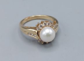 A 14ct gold ring set solitaire pearl surrounded by Diamonds with Diamond shoulders, 4.6gms, ring