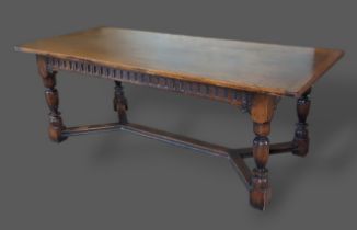 A Jacobean style oak refectory dining table, the plank top above arcadian frieze, raised upon turned