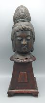 A bronze bust of Guanyin upon a carved wooden base, 40cms tall