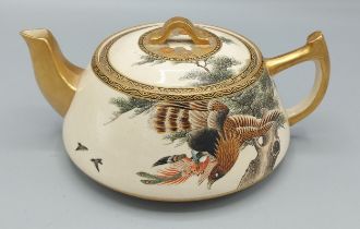 A Satsuma earthenware teapot decorated with birds amongst foliage highlighted with gilt