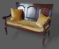 An 18th Century oak Settle with a three panel carved back above an upholstered seat with shaped arms