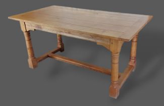 A green oak refectory style dining table, the plank top above a carved frieze raised upon turned