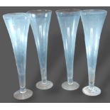 A set of four large glass table centrepiece vases of tapering form, 80cms tall