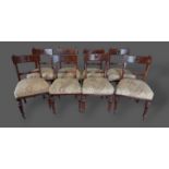 A set of eight Arts and Crafts dining chairs, each with a pierced carved rail back above a stuffover