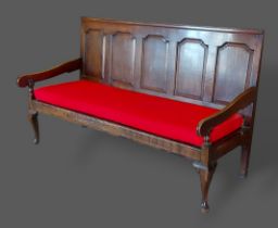 An 18th Century oak Settle with a five panel carved back above a panel seat raised upon cabriole