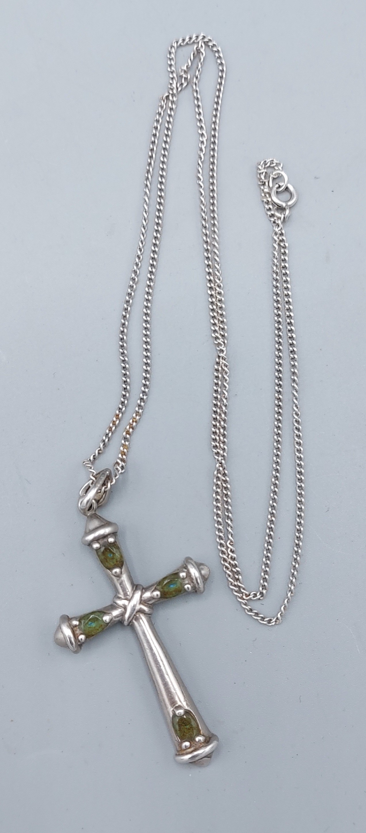 A Sterling silver crucifix pendant set with green stones together with a linked chain