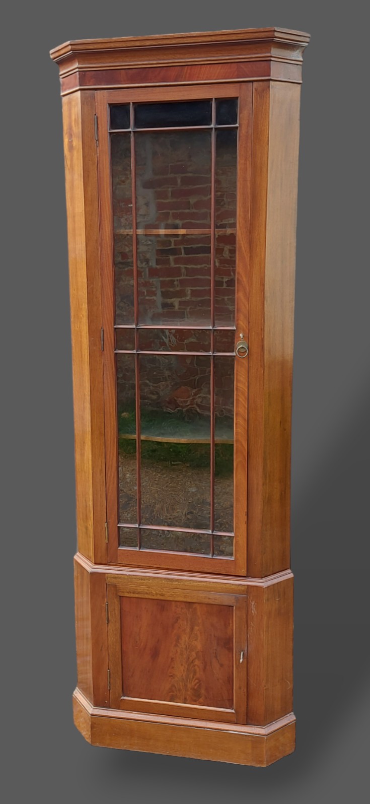 A mahogany standing corner cupboard, the moulded cornice above an astragal glaze door and raised
