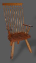 An elm Windsor armchair with a shaped spindle back above a panel seat raised upon turned legs