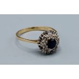 An 18ct gold Sapphire and Diamond cluster ring set with a central Sapphire surrounded by Diamonds,