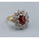 An 18ct gold cluster ring set with a central oval Garnet surrounded by Diamonds, 3.8gms, ring size M