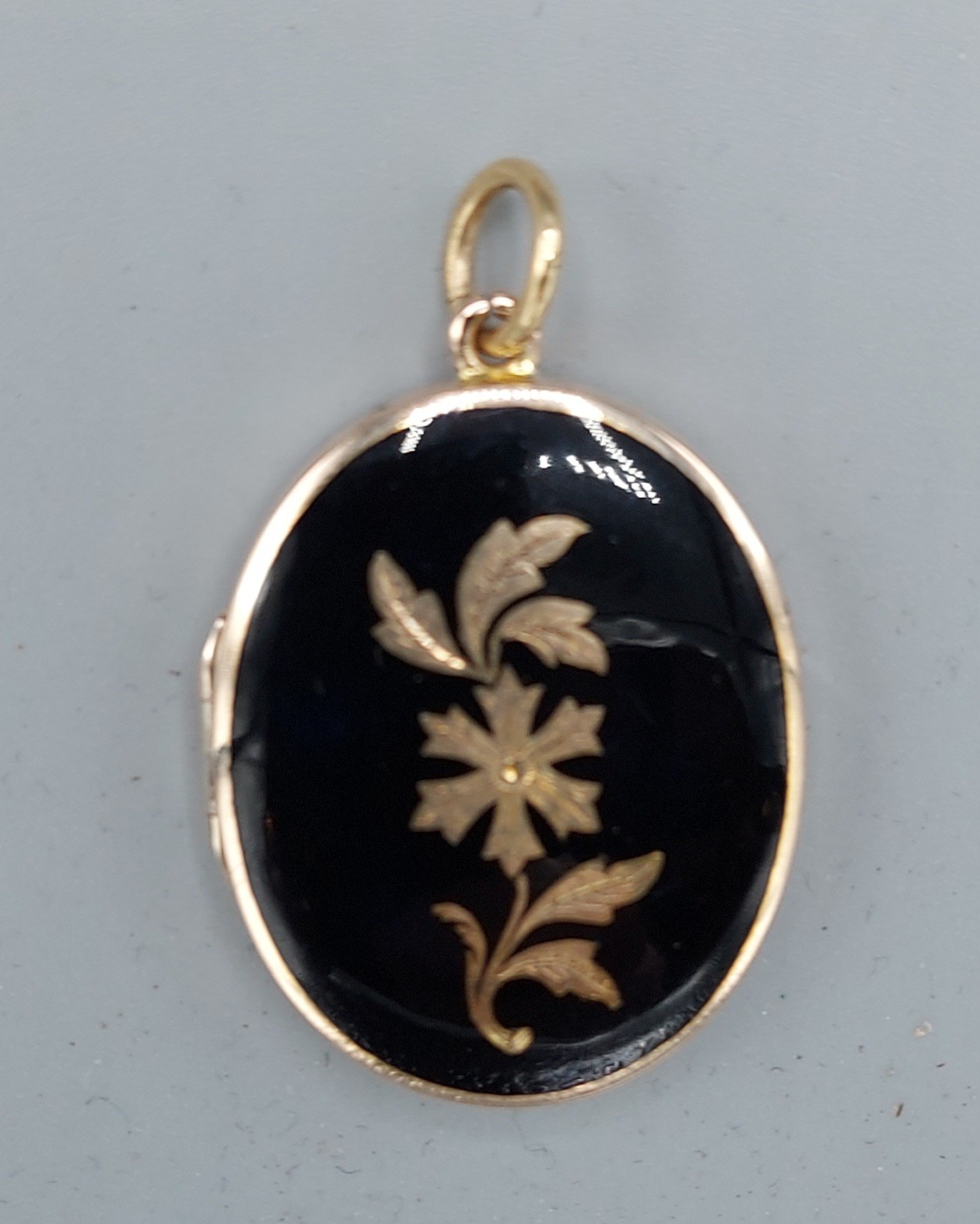 An 18ct gold and enamel locket of oval form with suspension ring, 11.1gms, 3cms x 2.5cms