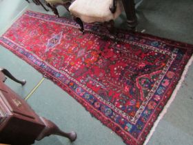 CAUCASIAN RUNNER RUG, decorated medallions on a red ground with blue borders, 300cm x 86cm