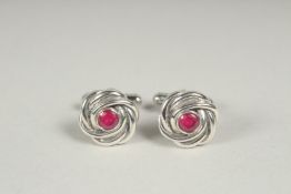 A pair of silver ruby knot cufflinks in a box.