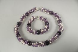 An amethyst and pearl necklace and bracelet in a box.