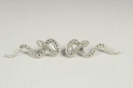 A pair of silver marcasite snake earrings in a box.