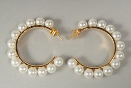 A pair of silver gold plated pearl hoop earrings in a box.