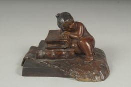 A small bronze of a girl sleeping on a pile of books, 10cm.