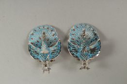 A pair of silver and blue enamel peacock earrings in a box.