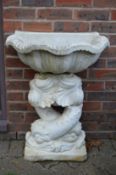 A white painted classical style water feature, the shell shaped top supported by a pair of