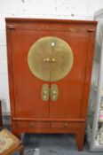 A Chinese red lacquer and brass mounted wardrobe or storage cabinet.