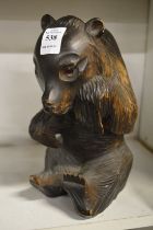 A black forest style carved wood seated bear.