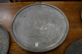An Islamic circular metal tray with engraved decoration.