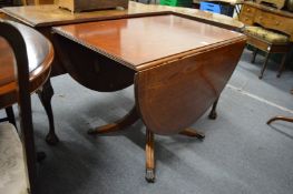 Reproduction mahogany drop leaf pedestal dining table.
