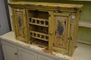 A decoratively painted hanging wall cupboard.