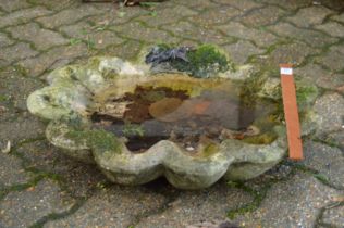A reconstituted stone shell shaped bird bath top.