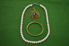 A gilt metal bangle, pearl necklace and a gilt metal pendant.