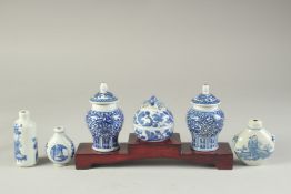 THREE CHINESE BLUE AND WHITE PORCELAIN SNUFF BOTTLES on a tiered wooden stand, together with a