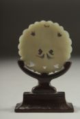 A CHINESE CARVED AND PIERCED JADE MOTH AMULET, on a fitted wooden stand, 6cm diameter.