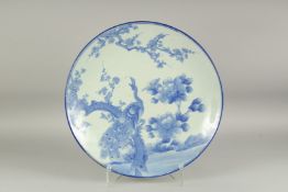A LARGE BLUE AND WHITE PORCELAIN CHARGER, painted with a peacock and flora, 48cm diameter.