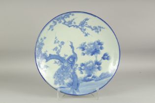 A LARGE BLUE AND WHITE PORCELAIN CHARGER, painted with a peacock and flora, 48cm diameter.